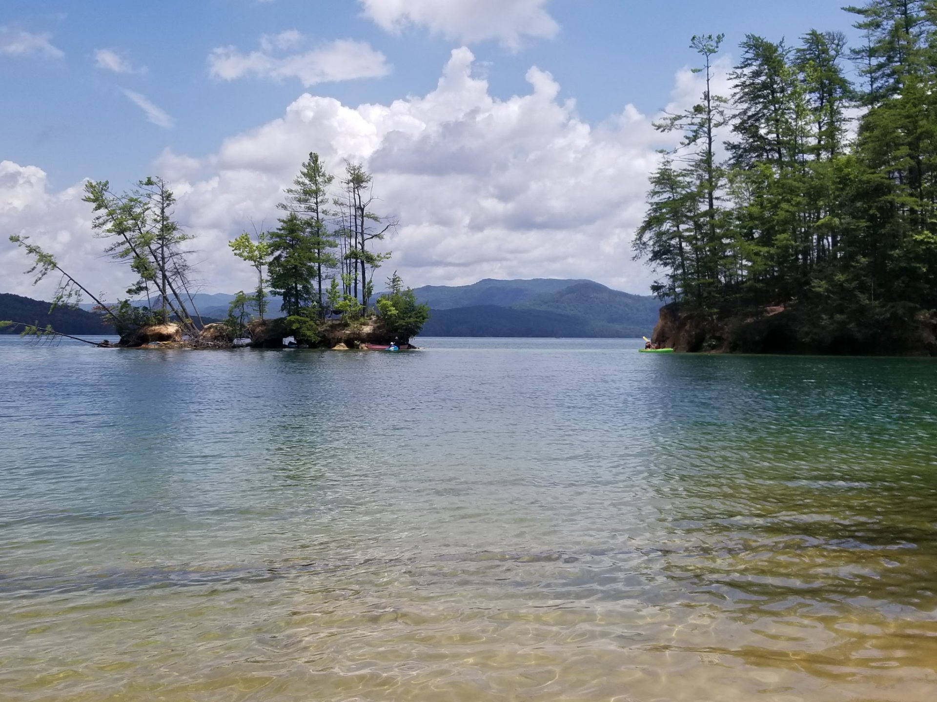 A small pine-covered island on Lake Jocassee, with mountains behind.