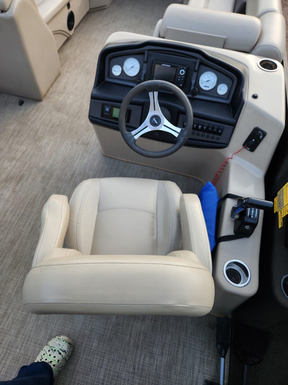 The tritoon’s helm: steering wheel, gauges, and a cushioned captain’s seat.